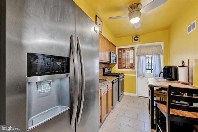 1386 Pentwood Rd, Baltimore, MD 21239 - kitchen featuring brown cabinetry, light tile patterned floors, ceiling fan, stainless steel appliances, and visible vents