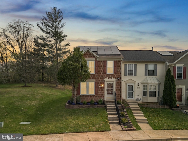 view of property with roof mounted solar panels and a front lawn