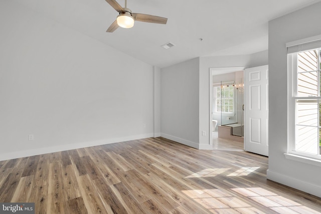 interior space featuring baseboards, vaulted ceiling, visible vents, and light wood-style flooring