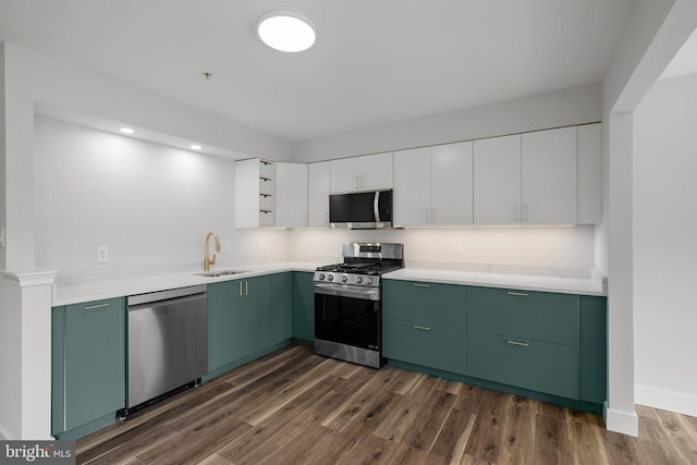 kitchen with white cabinets, green cabinetry, stainless steel appliances, a sink, and dark wood-type flooring