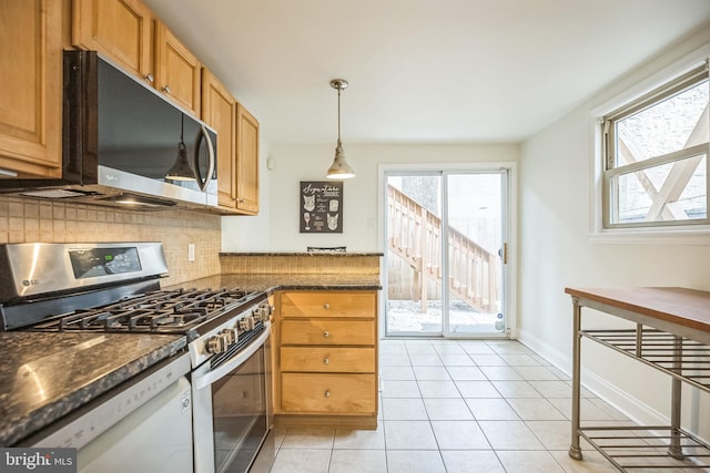 kitchen featuring stainless steel appliances, tasteful backsplash, light tile patterned flooring, decorative light fixtures, and dark stone counters