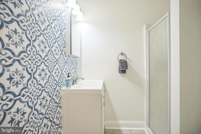 bathroom with a stall shower, tile patterned floors, vanity, and baseboards