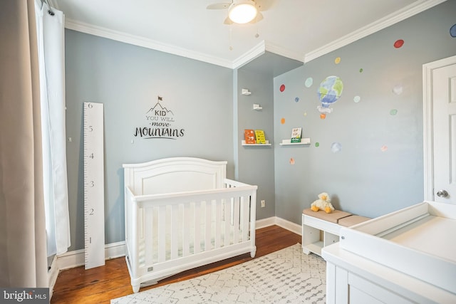 bedroom with ornamental molding, wood finished floors, a nursery area, baseboards, and ceiling fan