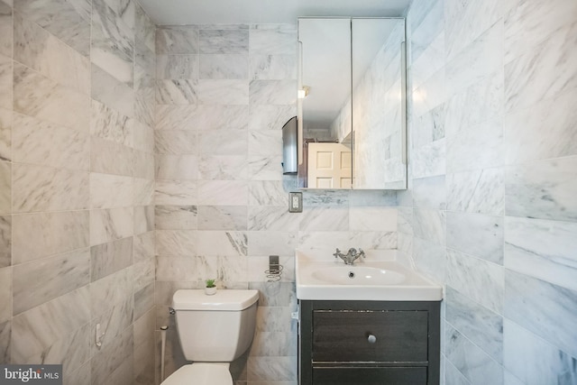 bathroom with tile walls, toilet, and vanity