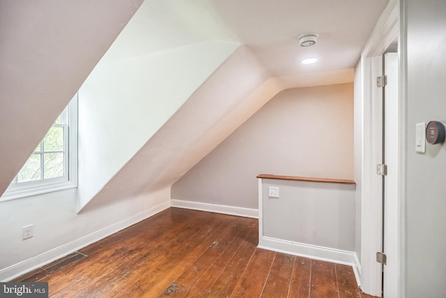 additional living space with vaulted ceiling, hardwood / wood-style flooring, and baseboards