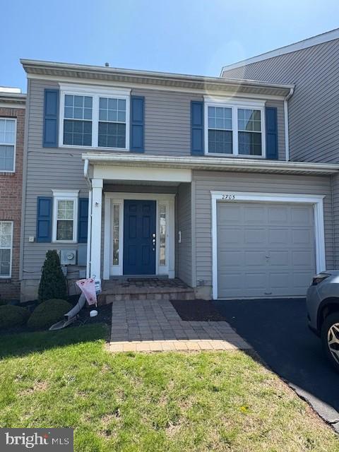 townhome / multi-family property featuring a garage, a front lawn, and asphalt driveway