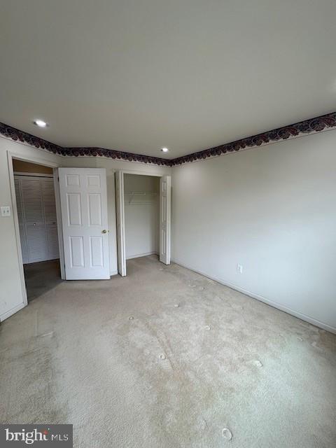 unfurnished bedroom with light carpet, recessed lighting, a closet, and baseboards