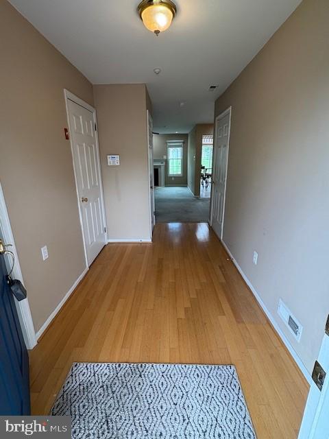 hall featuring light wood-style flooring and baseboards