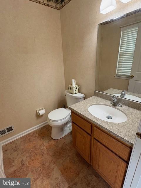 bathroom featuring toilet, vanity, and baseboards