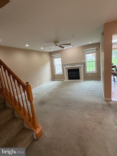 unfurnished living room featuring light carpet, healthy amount of natural light, recessed lighting, and baseboards