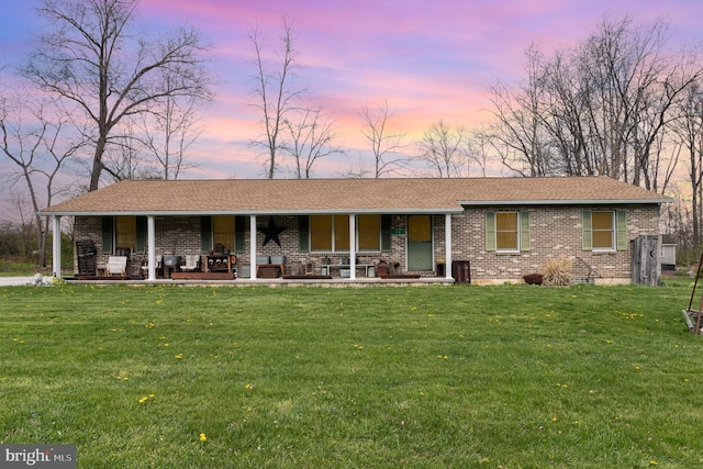 view of front of home featuring a porch, a front lawn, and brick siding