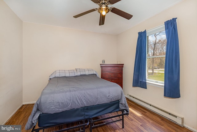 bedroom featuring baseboards, baseboard heating, wood finished floors, and a ceiling fan