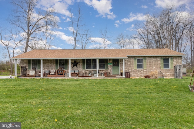 ranch-style house featuring a front yard, covered porch, brick siding, and roof with shingles