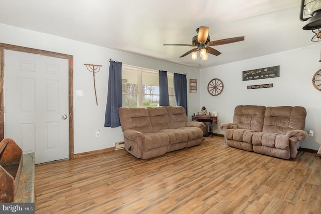 living room with a baseboard radiator, a ceiling fan, and light wood-style flooring