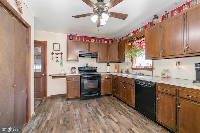 kitchen featuring wood finished floors, a sink, black appliances, ceiling fan, and under cabinet range hood