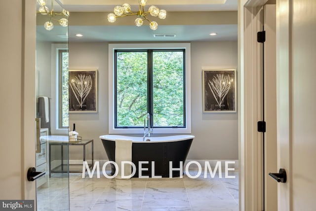 bathroom with a chandelier, a freestanding tub, visible vents, and marble finish floor