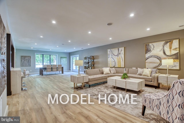 living room with baseboards, wood finished floors, and recessed lighting