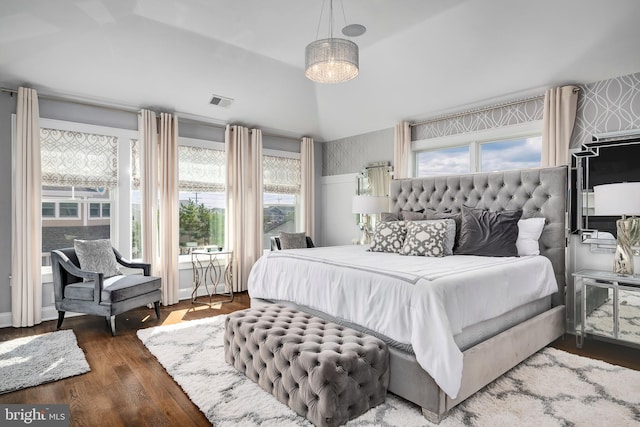 bedroom with lofted ceiling, wood finished floors, and visible vents
