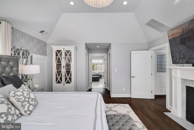 bedroom featuring vaulted ceiling, wood finished floors, visible vents, and a premium fireplace