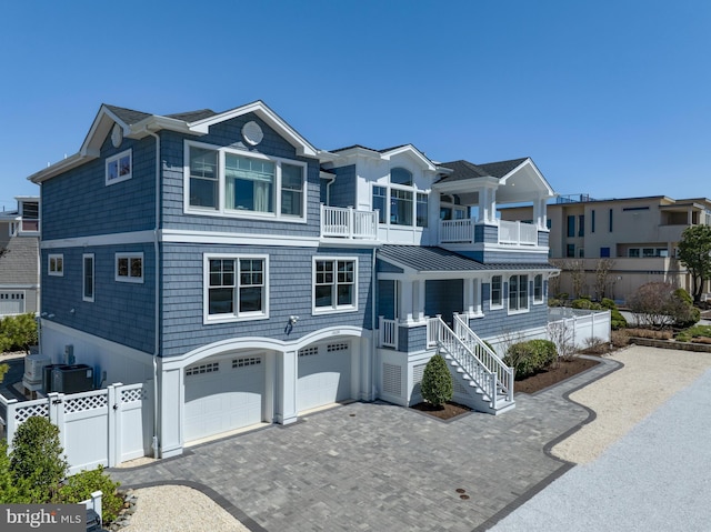 view of front of house with stairs, fence, a balcony, an attached garage, and decorative driveway