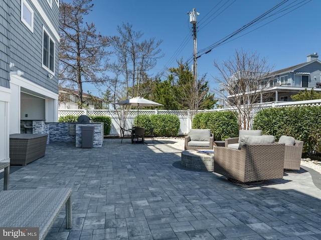 view of patio / terrace featuring a fenced backyard, an outdoor living space with a fire pit, and exterior kitchen
