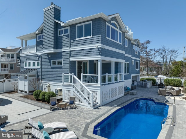 back of property featuring a chimney, a patio, stairs, and a fenced backyard