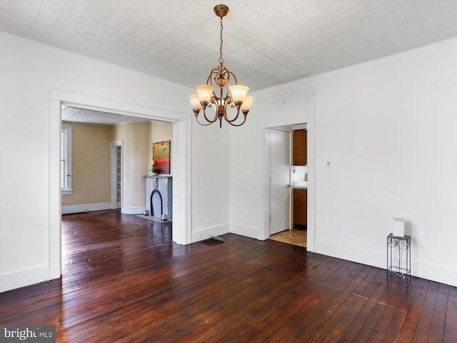unfurnished dining area featuring baseboards, an inviting chandelier, and hardwood / wood-style flooring