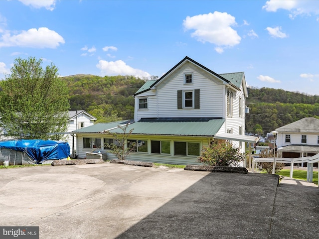 view of front of home with a wooded view and metal roof