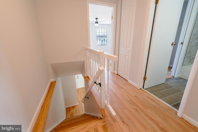 staircase featuring baseboards, wood finished floors, and ceiling fan