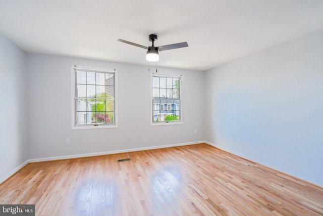 unfurnished room with visible vents, light wood finished floors, baseboards, and ceiling fan