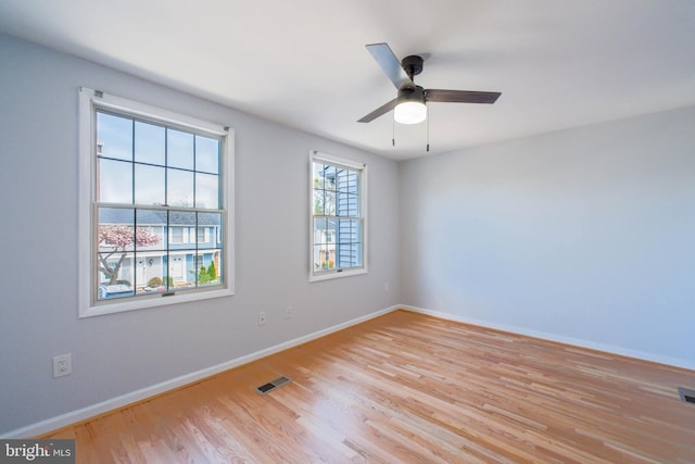 empty room featuring baseboards, a ceiling fan, visible vents, and light wood-style floors