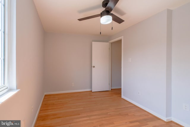empty room with baseboards, a ceiling fan, and light wood-type flooring