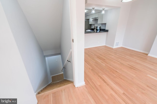 stairway with wood finished floors, visible vents, and baseboards