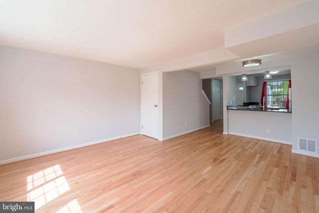 unfurnished living room with light wood finished floors, baseboards, and visible vents