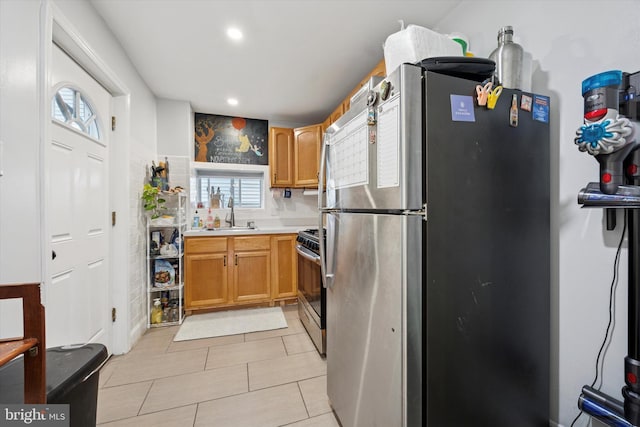 kitchen featuring recessed lighting, light countertops, light tile patterned floors, a sink, and appliances with stainless steel finishes