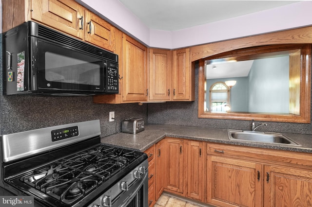 kitchen with black microwave, stainless steel range with gas cooktop, a sink, and dark countertops