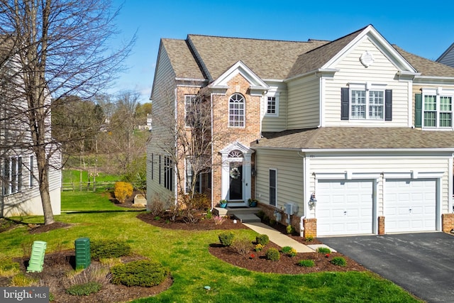 traditional-style house with brick siding, a garage, driveway, roof with shingles, and a front yard