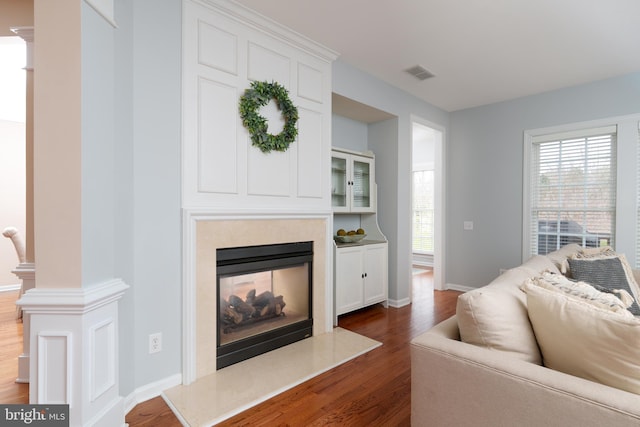 living room featuring dark wood-style floors, healthy amount of natural light, a fireplace, and baseboards