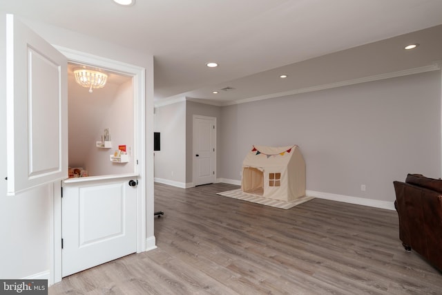 rec room with crown molding, baseboards, recessed lighting, wood finished floors, and a chandelier