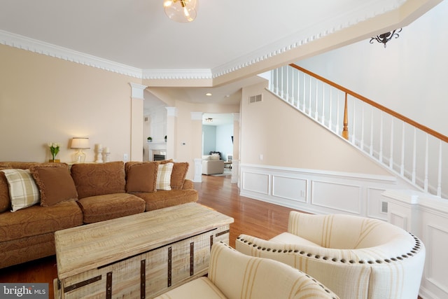 living area with wood finished floors, stairs, a wainscoted wall, and a decorative wall