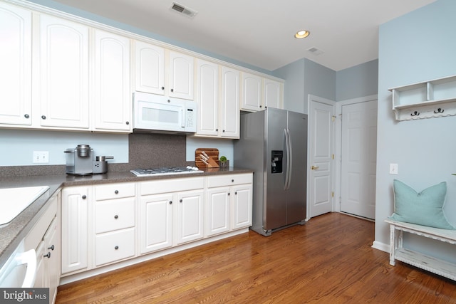 kitchen with white appliances, light wood finished floors, white cabinets, recessed lighting, and dark countertops