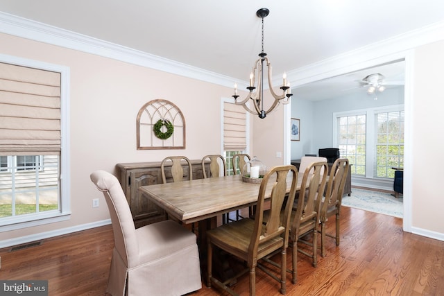 dining room with dark wood finished floors, baseboards, ornamental molding, a chandelier, and healthy amount of natural light