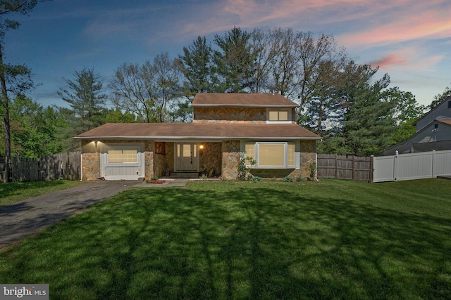 view of front facade with a yard, fence, and stone siding