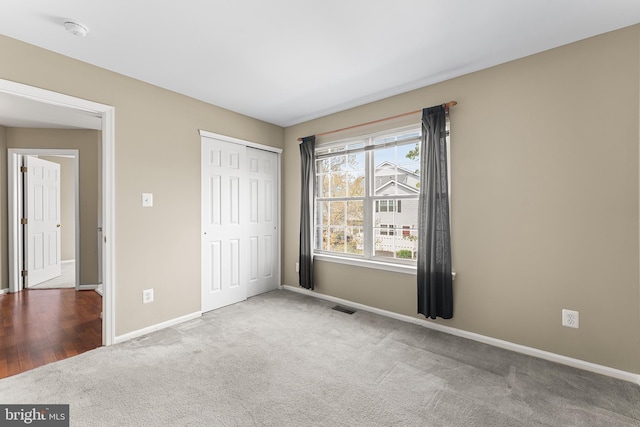 unfurnished bedroom with baseboards, visible vents, carpet, and a closet