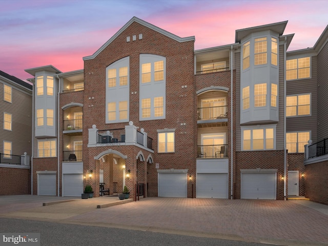 townhome / multi-family property with brick siding, driveway, and a garage