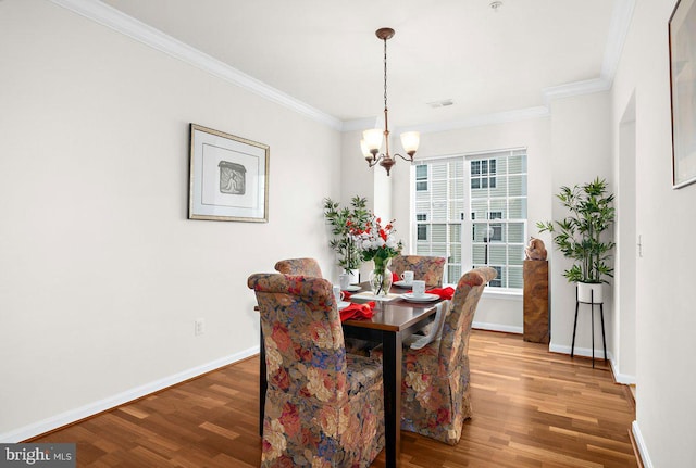 dining area with crown molding, baseboards, wood finished floors, and a chandelier