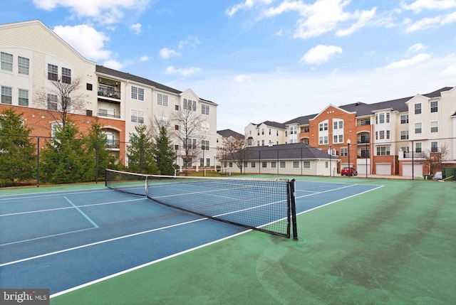 view of tennis court with fence, community basketball court, and a residential view