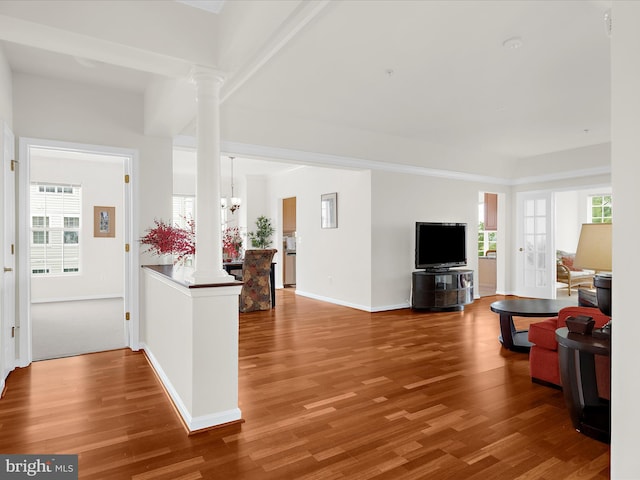 living room with an inviting chandelier, baseboards, decorative columns, and wood finished floors