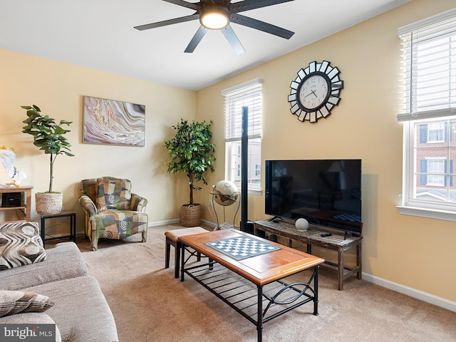 living room featuring light carpet, a ceiling fan, and baseboards