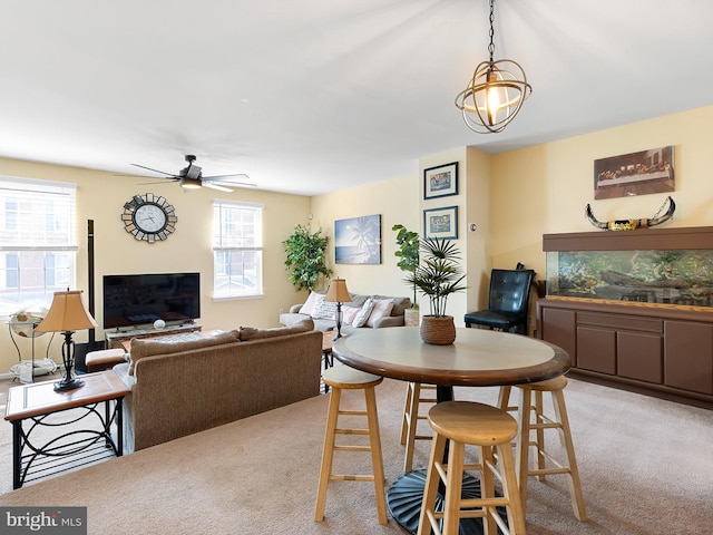 dining space featuring a ceiling fan, a glass covered fireplace, and carpet